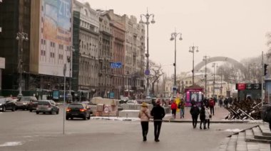 Group of people walking on Maidan Nezalezhnosti, the central square of Kyiv on a cold gloomy day. People go about their daily business and tourists take in the sights: Kyiv, Ukraine - January 15, 2023