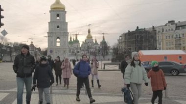 People move across the street to pedestrian crossing on the background of the bell tower of St. Sophia Church. Life on the streets in the center of Kyiv in military time: 1 March, 2023, Kyiv, Ukraine