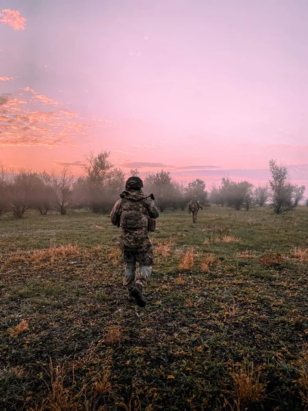 身着迷彩服 武装到牙齿的士兵 在黎明前的阳光下出发前往东方执行任务 然后太阳升起 特殊用途战斗机在该地区周围的战术移动 — 图库照片