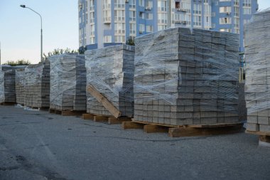 Sokakta istiflenmiş kaldırım levhaları: kaldırım inşaatında kullanıma hazır inşaat malzemeleri yığını. Kaldırımı döşemek için gri tuğla.