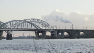 Kyiv 'deki Dnipro Nehri' nin karşısındaki Darnytsky demiryolu köprüsünün manzarası. 2023 yazı, Kyiv, Ukrayna. Kyiv 'deki köprüde trafik: nehre bakan sanayi manzarası.