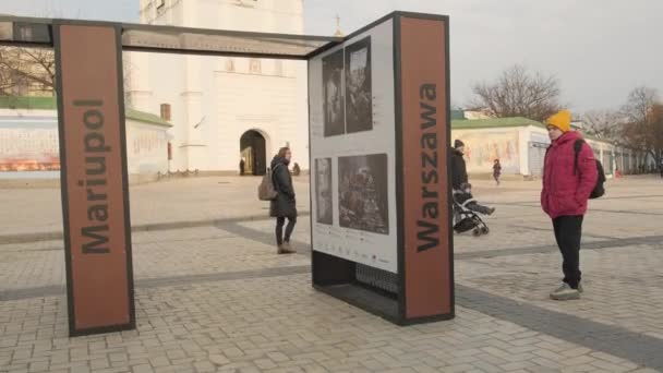 人々は ロシアのウクライナ侵攻の間 2023年春にキエフのミハイルヴァスカ広場で写真を見る スタンドにマリポールとワルシャワの碑文 2023 キエフ ウクライナ — ストック動画