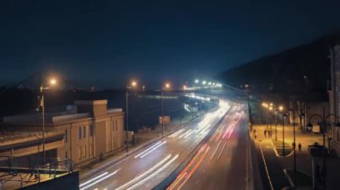 Büyük yoldaki gece trafiği: şehrin akşam ışıklarıyla birlikte zaman aşımı. Dnipro Nehri 'nin yanındaki set ve uzaktaki köprü..
