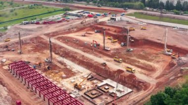 Yerleşim bölgesinde ağır makineler bulunan hareketli bir inşaat alanının havadan görüntüsü. Çim, bina ve asfaltı çevreleyen araziler