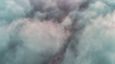 Bir uçak penceresinden mavi gökyüzündeki kümülüs bulutlarının görüntüsü, karanlık bir manzaranın üzerinde çarpıcı bir meteorolojik fenomen yaratıyor.