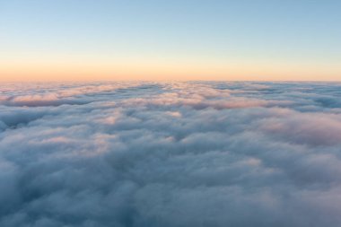 Gün batımında uçak penceresinden gökyüzündeki kümülüs bulutlarının görünüşü nefes kesen meteorolojik bir fenomendir.
