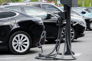 Alaşımlı tekerli elektrikli araba kuyruğu bir otoparkta şarj oluyor. Elektrikli arabalar ekolojik yenilenebilir enerji ile şarj edilir.