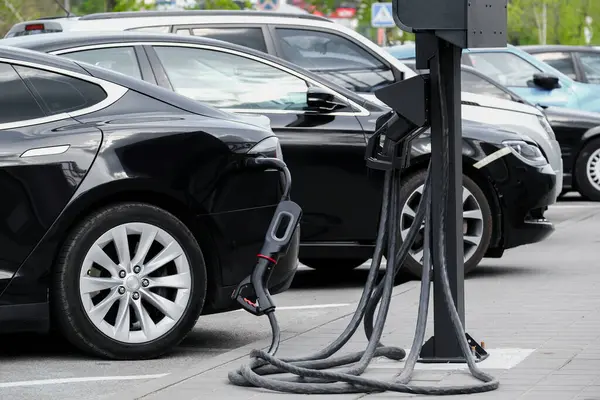 Alaşımlı tekerli elektrikli araba kuyruğu bir otoparkta şarj oluyor. Elektrikli arabalar ekolojik yenilenebilir enerji ile şarj edilir.