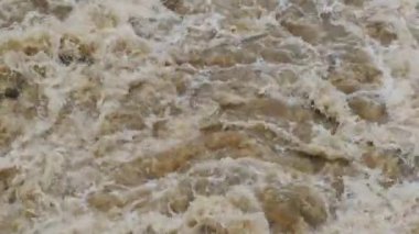 Nehirde köpüklü çamurlu su. Barajdan büyük su birikintileri düşüyor. Yarı su boyunca güçlü bir kubbe suyu akışı..