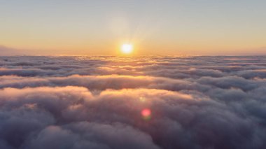 Güneş batıyor, gökyüzündeki bulutların üzerine kırmızı bir parıltı saçıyor, alacakaranlıkta güzel bir parlama yaratıyor.