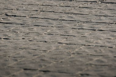 Düşük açılı, arka planda bulanık bir kaldırım taşı sokağının detaylı görüntüsü, kaya ve anakaya karışımından yapılmış yapı malzemesinin karmaşık modelini gösteriyor. Seçici odak.