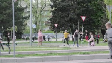 Bir grup çocuk parkta paten kaymak, bisiklete binmek ve yürümek gibi aktivitelerden hoşlanırlar. Çocuklar hafta sonu kaldırımda motosiklet ve scooterlarla oynuyorlar: 14 Nisan 2024 - Zaporizhzhia, Ukrayna