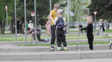 Bir grup çocuk bisikletlerini asfalt caddede ağaçlarla kaplı bir şekilde pedal çeviriyor, spor malzemelerinin keyfini çıkarırken tekerlekleri yerde dönüyor: 14 Nisan 2024 - Zaporizhzhia, Ukrayna