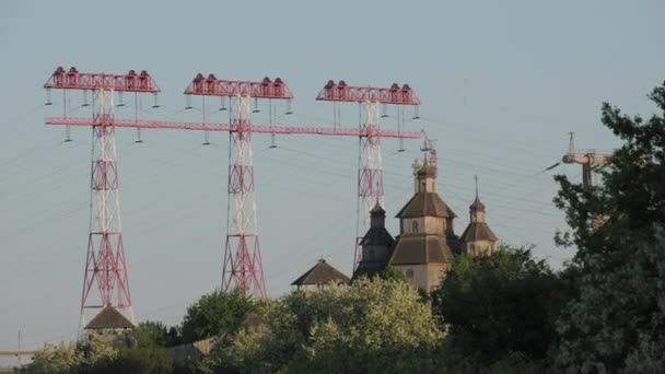 Tre Piloni Elettrici Torreggianti Con Antica Chiesa Legno Sullo Sfondo — Video Stock