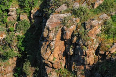 Yeşilliklerle süslenmiş antik jeolojik oluşumlar. Yerkabuğunun karmaşık çalışmaları. Engebeli arazi kayaların karmaşık katmanlarına hayret ediyor..
