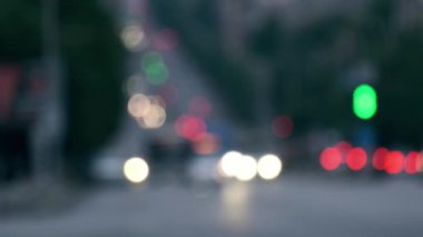 Bulanık şehir manzarası, hareket eden arabalar ve renkli bokeh ışıkları. Sahne, şehir yaşamı, ulaşım ve akşam ulaşımıyla ilgili konular için ideal, dinamik şehir atmosferini yakalıyor.