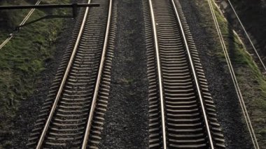 Yüksek bir manzara, altın saat boyunca yemyeşil ile çevrili iki kıvrımlı tren yolunu gösteriyor.