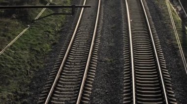 Yukarıdan bakıldığında, parlak güneşli bir gökyüzünün altında yemyeşil tarafından çevrelenmiş bir dizi paralel tren yolu görülebilir.