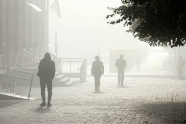 Silhouetted individuals leisurely stroll through a fogcovered cityscape, creating a captivating atmosphere filled with mystery, intrigue, and a deep sense of solitude and quiet contemplation clipart