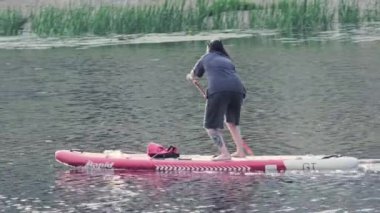 Bir kişi bereketli yemyeşil sularla çevrili sakin ve sakin sularda kürek çekiyor ve aktif bir açık hava yaşam tarzı sergiliyor: Ağustos 2024 - Kyiv, Ukrayna