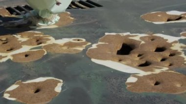 Şehir çatışması sırasında şarapnel parçalarıyla ağır hasar görmüş bir arabanın yakından görüntüsü. Araç yüzeyi mermi parçalarından kaynaklanan deliklerle delik deşik olmuş. Şehir ortamında savaşın yıkıcı etkisi..