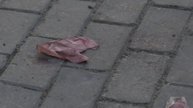 Suç mahallindeki kaldırım taşlarının üzerinde kanlı peçeteler duruyor. Son şiddet olayının tüyler ürpertici kanıtlarını sağlıyor. Trajik ve rahatsız edici bir olayın canlı bir hatırlatıcısı..