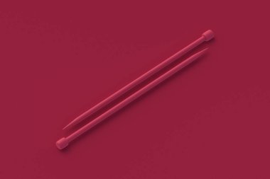 Kırmızı arka planda iki örgü şişi. 3d hazırlayıcı