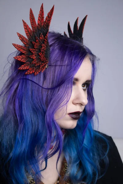 A woman with bright purple hair and clipped wings. Girl with purple hair portrait. Model for advertising hair dye. Purple hair. Colored hair, people with tattoos, informals. Gothic girl with purple hair and a choker around her neck.