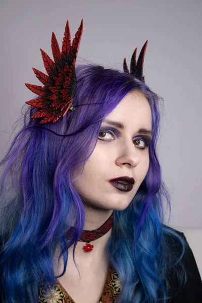 A woman with bright purple hair and clipped wings. Girl with purple hair portrait. Model for advertising hair dye. Purple hair. Colored hair, people with tattoos, informals. Gothic girl with purple hair and a choker around her neck.