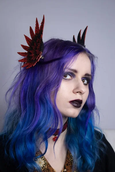 A woman with bright purple hair and clipped wings portrait. Model for advertising hair dye.Colored hair, people with tattoos, informals. Gothic girl with purple hair and a choker around her neck. Girl with valkyrie wings cosplay.