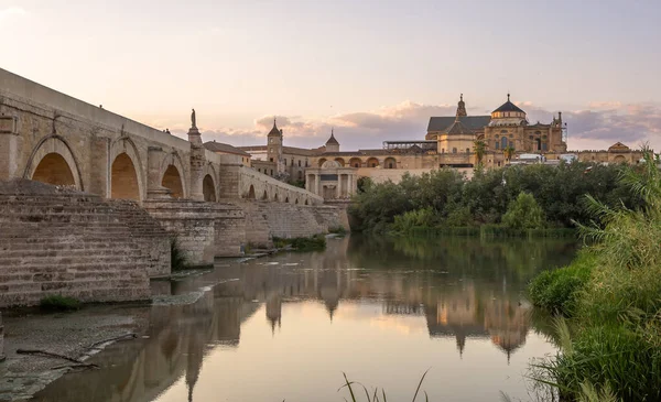 Exposure at sunset of the Roman bridge of and the Mosque Cathedral of Cordoba in the background with the Guadalquivir river in the foreground