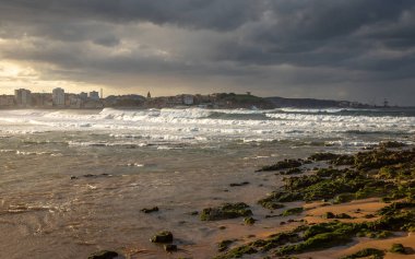 İspanya, Sunset 'te sörf yapmak için dalgalı güzel bir sahil şeridinin Gijon rıhtımından....