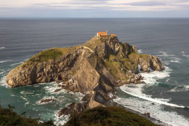 San Juan de Gaztelugatxe adası ve kıyı kasabaları Bakio ve Bermeo arasında yer alan inziva yerinin kıyıya taş bir köprü ve 241 basamaklı bir merdiven, İspanya 'nın Bask sahili,.