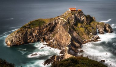 San Juan de Gaztelugatxe adası ve kıyı kasabaları Bakio ve Bermeo arasında yer alan inziva yerinin kıyıya taş bir köprü ve 241 basamaklı bir merdiven, İspanya 'nın Bask sahili,.