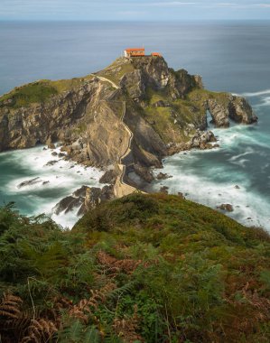 San Juan de Gaztelugatxe adası ve kıyı kasabaları Bakio ve Bermeo arasında yer alan inziva yerinin kıyıya taş bir köprü ve 241 basamaklı bir merdiven, İspanya 'nın Bask sahili,.