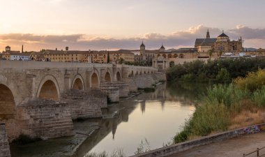 Arka planda Cordoba Camii Katedrali ve ön planda Guadalquivir Nehri ile Roma Köprüsü 'nün gün batımında çekim