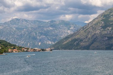 Güneşli bir günde Kotor Körfezi 'nin deniz girişini, güzel kıyı manzaralarını ve küçük köylerini gösteren bir gezi gemisinden manzara teşhir etmek..