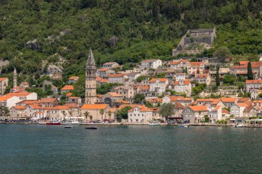 Güneşli bir günde Kotor Körfezi 'nin deniz girişini, güzel kıyı manzaralarını ve küçük köylerini gösteren bir gezi gemisinden manzara teşhir etmek..