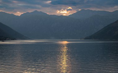 Gün batımında bir yolcu gemisinden çekilen manzara Kotor Körfezi 'nin deniz girişini ve güzel kıyı manzaralarını ve güneşli bir günde küçük köyleri gösteriyor..