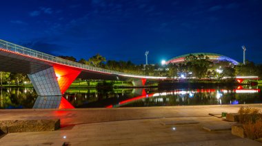 Torrens Nehri 'nin uzun pozu, yürümek için güzel bir yer, yaya köprüsü ve Adelaide Oval, Avustralya