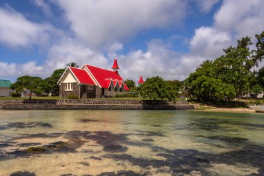 Mauritius 'un en ünlü kiliselerinden biri olan Notre Dame Auxiliatrice Kilisesi, parlak turkuaz deniz ve gök mavisi gökyüzüne karşı canlı kırmızı çatısıyla ünlü Roma Katolik Kilisesi' dir.