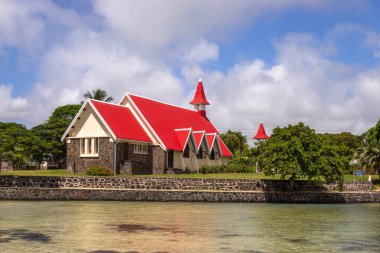 Mauritius 'un en ünlü kiliselerinden biri olan Notre Dame Auxiliatrice Kilisesi, parlak turkuaz deniz ve gök mavisi gökyüzüne karşı canlı kırmızı çatısıyla ünlü Roma Katolik Kilisesi' dir.