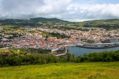 Angra do Heroismo 'nun panoramik görüntüsü Terceira Adası, Azores, Portekiz. Kırmızı çatılar, marina ve yeşil tepeler Monte Brasil 'den Atlantik Okyanusu manzaralı..