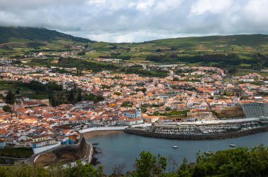 Angra do Heroismo 'nun panoramik görüntüsü Terceira Adası, Azores, Portekiz. Kırmızı çatılar, marina ve yeşil tepeler Monte Brasil 'den Atlantik Okyanusu manzaralı..