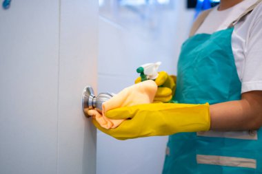 Evdeki temiz kapı kolunun bir parçası. Genç kız temizlikçi, temizlikçi, ev işleri ya da ev işleri.
