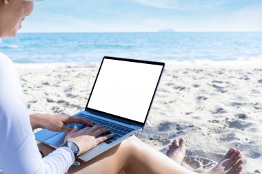 Herhangi bir konsept üzerinde çalış. Sahilde bilgisayarla çalışan genç bir kadının arka görüntüsü.