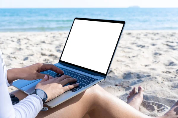 Work from anywhere concept. Rear view of young woman working on computer laptop on the beach