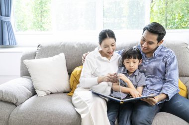 Ebeveynler ve çocuklar oturma odasında birlikte bir kitap okudular.