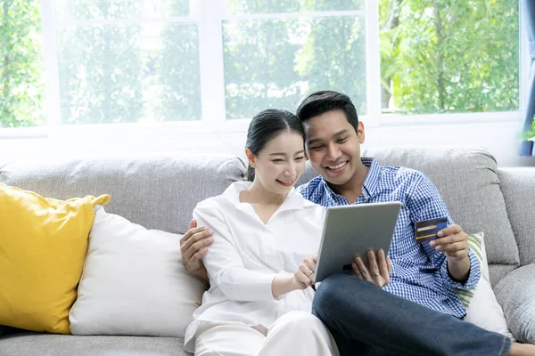 Young Asian couple use credit card for payment online at home