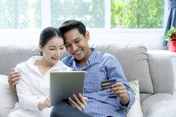 Young Asian couple use credit card for payment online at home
